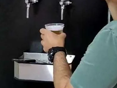 Torneiras de chopp de autosserviço instaladas no salão de festas, com um copo sendo servido