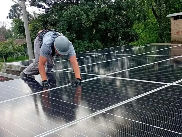 Técnico ajustando módulos fotovoltaicos durante a instalação da usina do condomínio